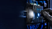 Technician inspecting an industrial automation module identification plate under blue light